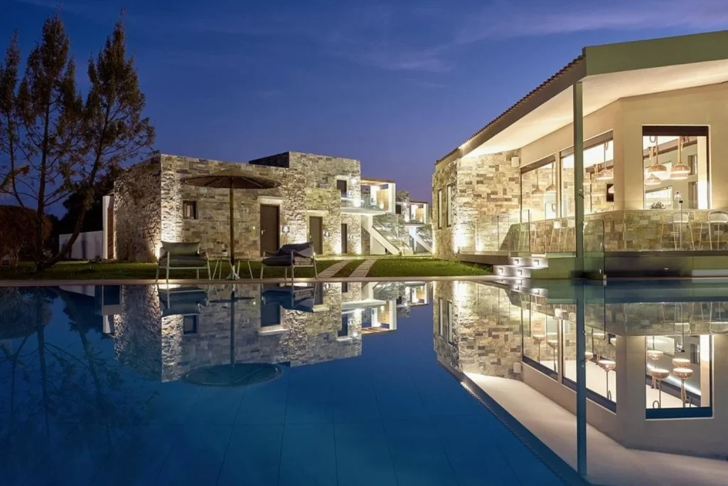 Luxury outdoor swimming pool with illuminated stone suites and modern poolside lounge areas at Golden Sun Resort & Spa, Zakynthos