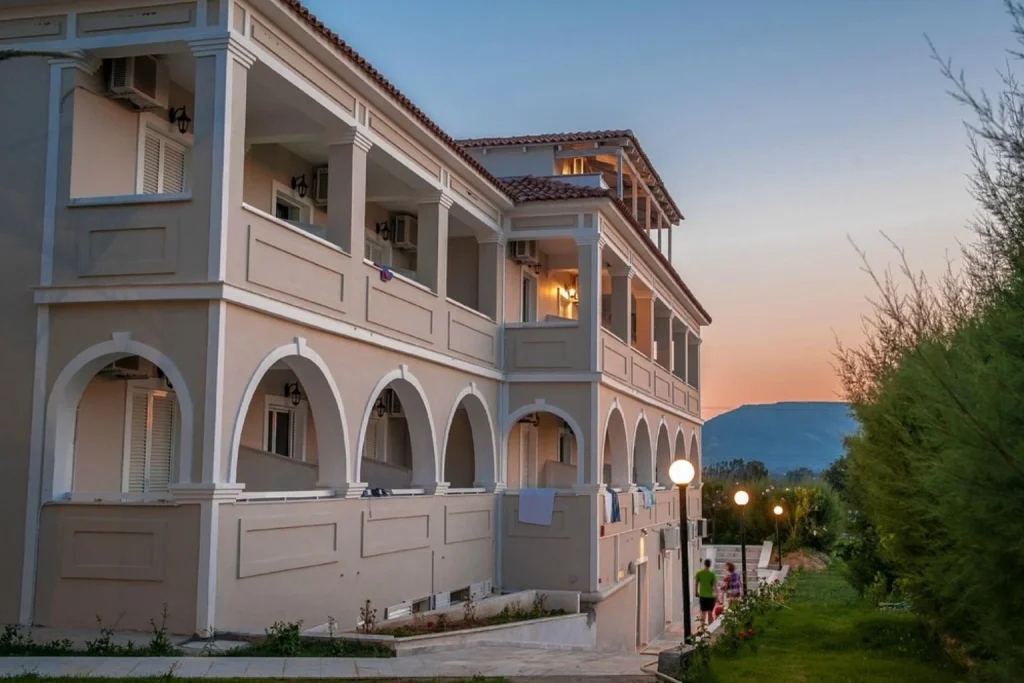 Hotel exterior with arched balconies, gardens and mountain views at sunset at Klelia Beach Hotel by Zante Plaza, Zakynthos
